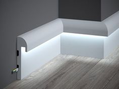 an illuminated corner bench in the middle of a room with wood flooring and gray walls