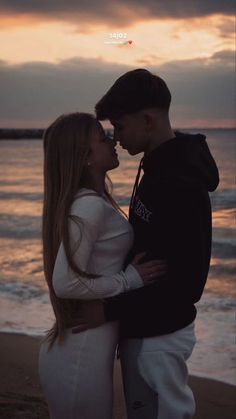 a couple kissing on the beach at sunset