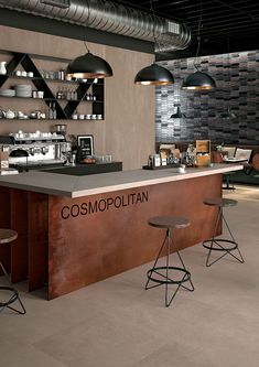 an industrial style bar with two stools and shelves on the wall behind it that says cosmopoltian