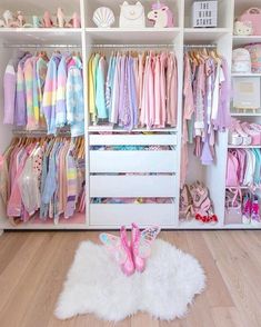 a white closet filled with lots of children's clothing and accessories on shelves next to a rug