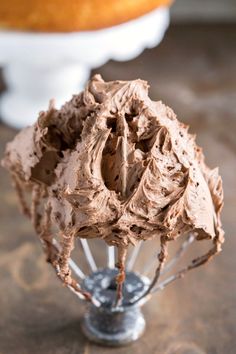 a close up of a chocolate frosted cake on a wire whisk stand