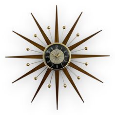 a clock that is on the side of a wall with gold balls around it and an arrow in the middle