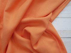 an orange fabric on a white wooden surface