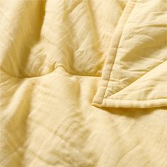 an unmade bed with yellow sheets and pillows