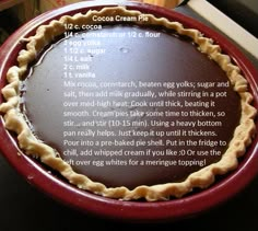 a chocolate cream pie sitting on top of a red plate next to a wooden table