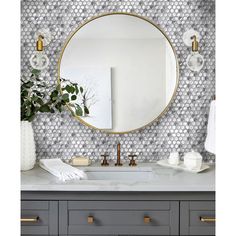 a bathroom vanity with a round mirror and gold faucet on the wall above it