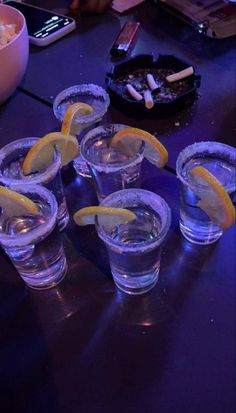 several shot glasses with lemon wedges on a table