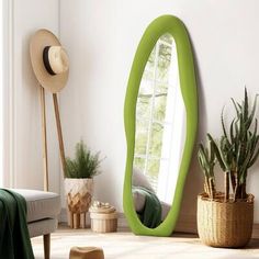 a green oval shaped mirror sitting on top of a wooden floor next to a window