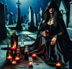 a woman sitting on the ground with candles around her and bottles in front of her