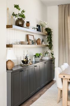 a dining room table and some shelves with plants