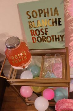 a table with balloons and bottles on it, including a bottle of rose dorothy