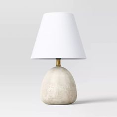 a table lamp with a white shade on the base and a light bulb attached to it