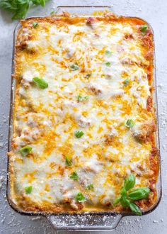 a casserole dish with meat and cheese on top, garnished with fresh basil