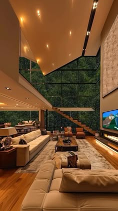 a large living room with high ceilings and wood flooring is lit by recessed lights