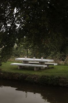 there is a picnic table in the grass by the water