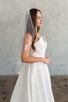 a woman in a wedding dress with a veil on her head looking off to the side