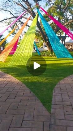 colorful hammocks hanging from trees on brick walkways in front of grassy area