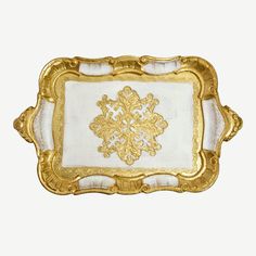 a gold and white tray with an ornate design on the bottom, in front of a white background