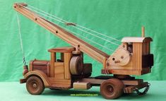 a wooden toy truck with a crane on it's flatbed is shown in front of a green background