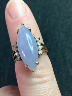 This undeniably beautiful ring is a Vintage Lavender Jade, Diamond, 14K gold evening ring.  This was part of an inherited estate from my Great Aunt via my Grandmother.  Ring is listed as Vintage before 2003, but was likely purchased in the 1970s.  This is an absolutely gorgeous ring, in a unique style that I have not seen at all otherwise.   The ring was formerly appraised (see pictures), and has .30 ctw for the Diamonds, and 6.5 grn Lavender Jade Stone, though I believe that this refers to the total weight of the ring, which according to my digital scale was exactly 6.49g. The band is stamped 585 interior and is 14K gold.  Each one of the 8 small diamonds sits lining either side of the large Lavender Jade Gemstone.  Lavender jade is one of the rarest forms of jade, and is believed to have Formal Marquise Diamond Ring Stamped 14k, Heirloom Marquise Ring For Collectors, Vintage Marquise Cut Ring With Accent Stones, Vintage Marquise Cut Rings With Accent Stones, Classic Marquise Amethyst Ring For Anniversary, Classic Marquise Amethyst Anniversary Ring, Formal Multi-stone Marquise Rings, Formal Marquise Multi-stone Rings, Heirloom Marquise Amethyst Ring For Anniversary