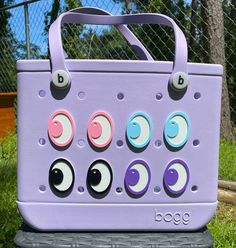 Bring a playful gaze to your favorite Bogg Bag with these charming Peek-A-Boo Emoji Eyes! Each set includes two wide-eyed friends that easily attach to your tote, giving it a personality as unique as your own. Crafted with care, these adorable eyes are designed to add a fun twist to your everyday carryall. Key Features: - Easy Installation: Designed to pop right into the holes of your Bogg Bag, these charms can be added or changed in seconds without any tools required. - Durable Material: Made w Novelty Multicolor Bag For Everyday Use, Playful Purple Bag For Everyday Use, Pink Novelty Bags For Everyday Use, Pink Novelty Bag For Everyday Use, Playful Bucket Bag For Everyday Use, Fun Bucket Bag For Everyday Use, Fun Everyday Bucket Bag, Playful Purple Travel Bags, Novelty Rectangular Everyday Bag