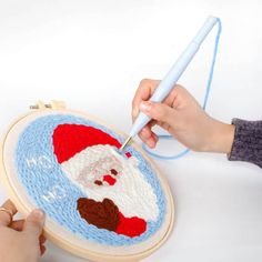 someone is using a needle to stitch a santa clause ornament on a round rug