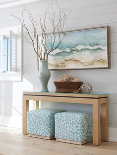 a vase filled with flowers sitting on top of a wooden table next to a painting