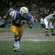 a football player is running with the ball in his hand and another person behind him