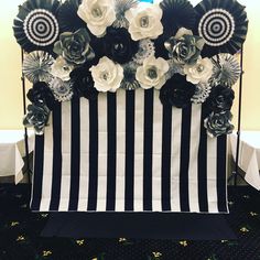 a black and white striped table cloth with paper flowers on the top is set up for a party