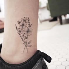 a small tattoo on the ankle of a woman's foot with flowers in it