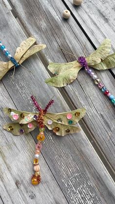 three dragonflys sitting on top of a wooden table next to beads and beads