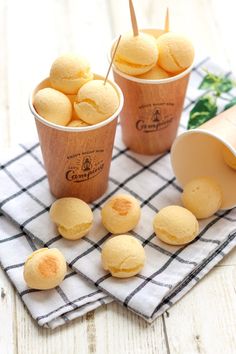 two cups filled with ice cream sitting on top of a checkered cloth next to small cookies