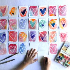 someone is painting hearts with watercolors on paper