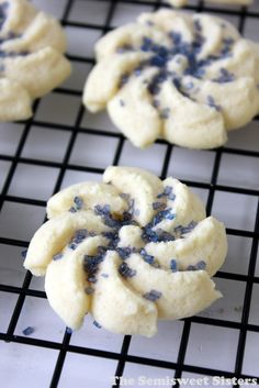 four cookies with blue sprinkles on a cooling rack in front of them