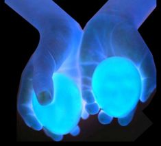 two hands holding glowing blue balls in the middle of their palm, against a black background