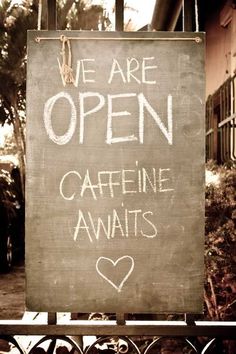 a sign that says we are open caffeine awaits