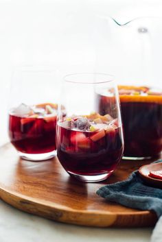 two glasses filled with liquid sitting on top of a wooden tray next to a bowl