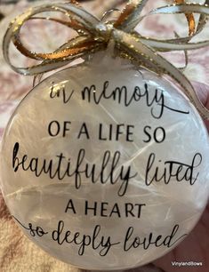 a hand holding a glass ornament that says, in memory of a life so beautifully lived a heart so deeply loved