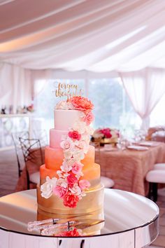 a multi - tiered cake with flowers on the top is sitting on a table