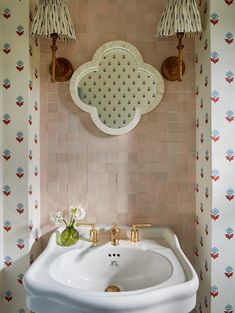 a white sink sitting under a bathroom mirror next to a wall mounted faucet