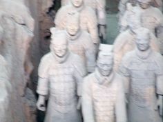 several statues of men standing next to each other in front of large rock formations with faces on them