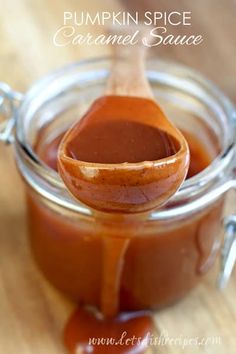 a spoon full of caramel sauce sitting on top of a jar with the words pumpkin spice caramel sauce in it