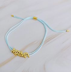 This beautiful MAMA bracelet is made of a slim satin thread with simple golden font. Its clean, minimalist design features adjustable drawstring size for easy fitting, with each letter that moves independently around the thread. Perfect for the fashionable, yet understated, mother. Dimensions: approximate 10" Perimeter Fully Adjustable With a Slide 18K Gold Plated Brass Lead and Nickel Free Images and Description Courtesy of Ellison & Young Adjustable Gold Friendship Bracelets With Letter Beads, Gold Friendship Bracelets With Adjustable Band, Adjustable Name Bracelet For Friendship, Adjustable Sliding Knot Jewelry For Mother's Day, Gold Nylon Cord Bracelet For Everyday, Gold Bracelets With Adjustable Nylon Cord, Everyday Gold Bracelet With Nylon Cord, Gold Bracelet With Adjustable Nylon Cord, Adjustable Custom Name Friendship Bracelets For Everyday