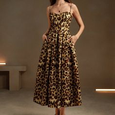 a woman in a leopard print dress poses for the camera with her hands on her hips