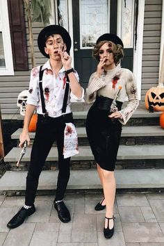 two people dressed up as zombies on the front steps of a house with pumpkins