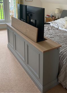 a flat screen tv sitting on top of a wooden dresser next to a large bed