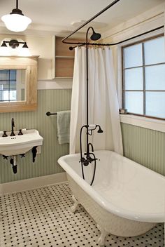 an old fashioned bathtub in a bathroom with black and white floor tiles on the walls