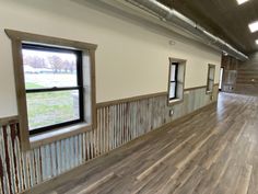 an empty room with wooden floors and windows