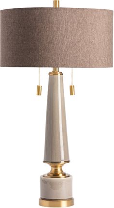 a table lamp with a beige shade on the top and gold trimmings around the base