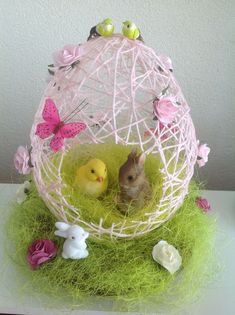 two little chicks in a white netted ball with pink flowers and butterflies around it